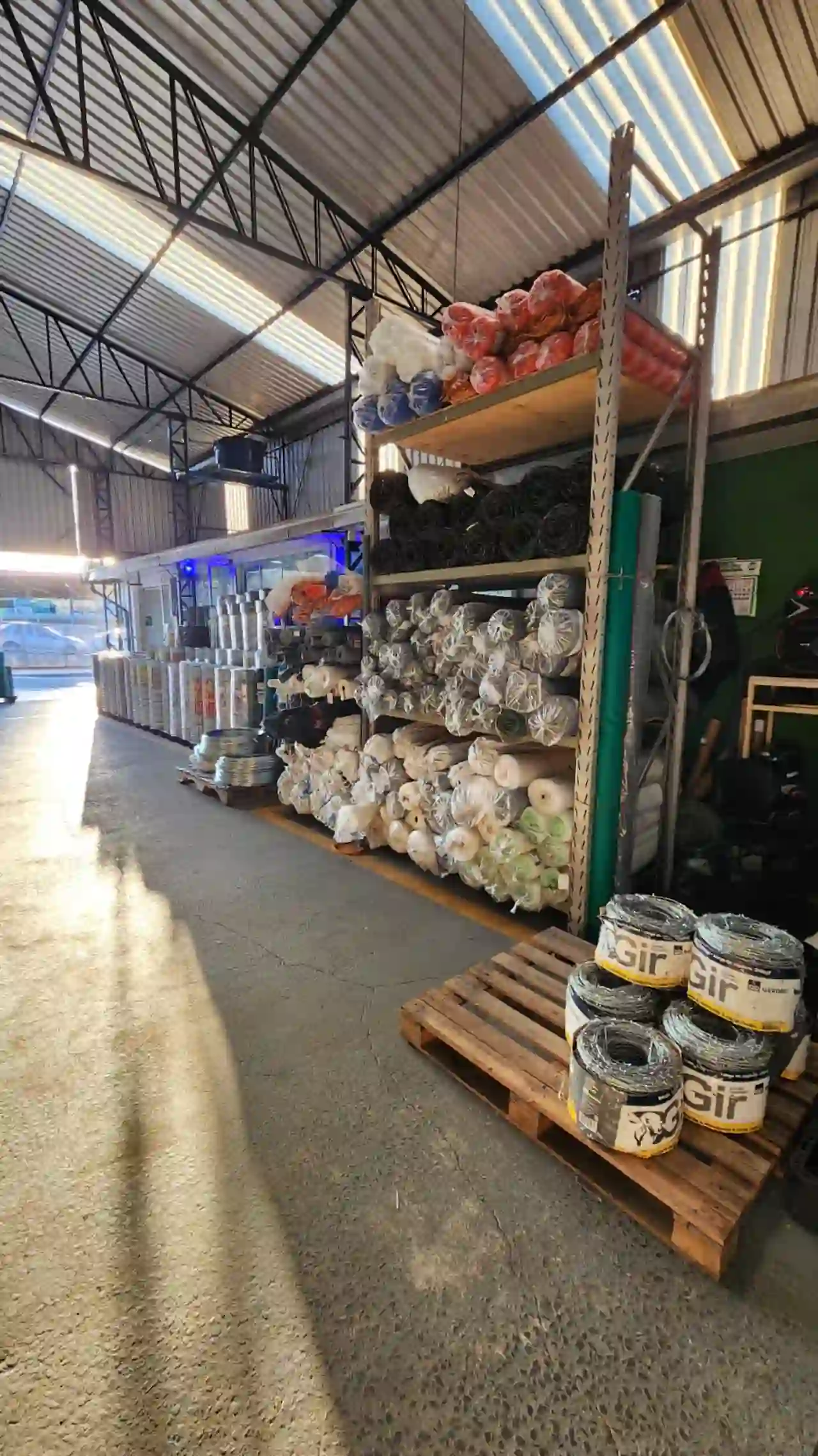 Corredor do galpão com luz natural e estantes cheias de produtos