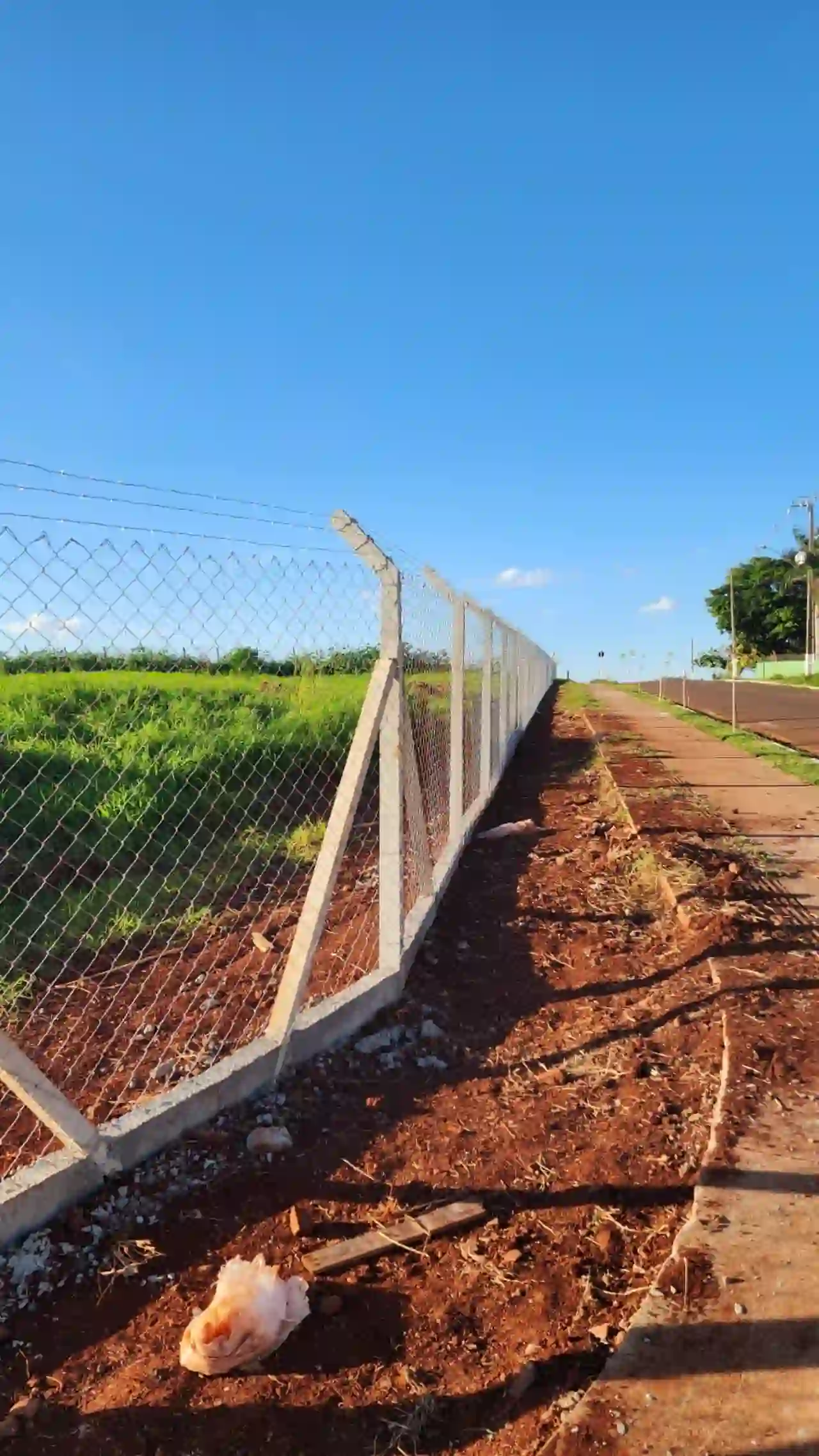 Alambrado instalado em campo com terra vermelha e vegetação