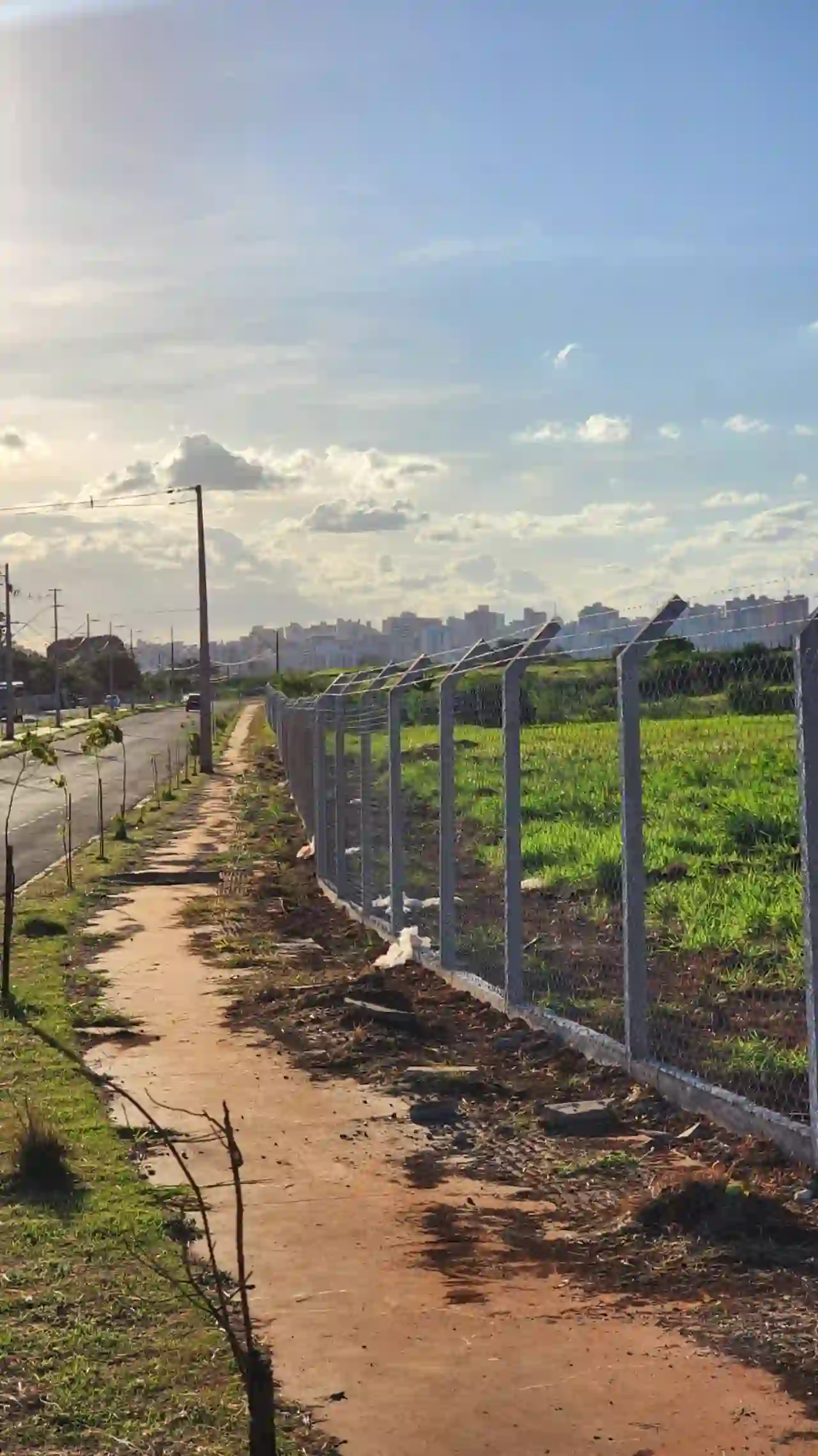 Alambrado instalado ao longo de rodovia com cidade ao fundo