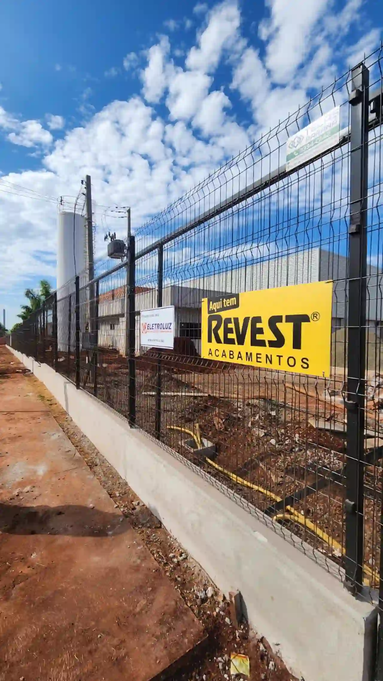Gradil preto em obra industrial com placa de empresa ao fundo